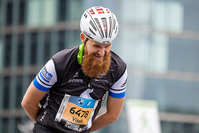 An inline skater with a full beard and a white helmet skates along the track.