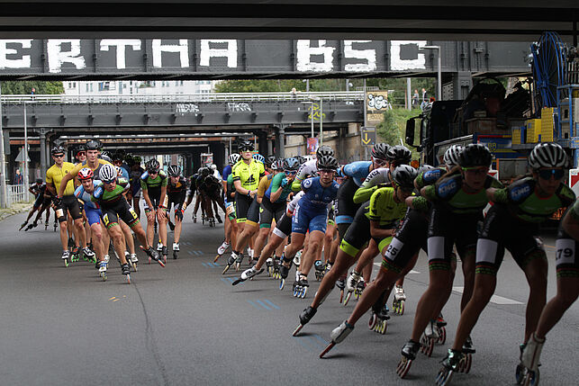 Zahlreiche schnelle Inline Skater unterqueren die York-Brücken, auf die der Schriftzug Hertha BSC gesprüht ist.
