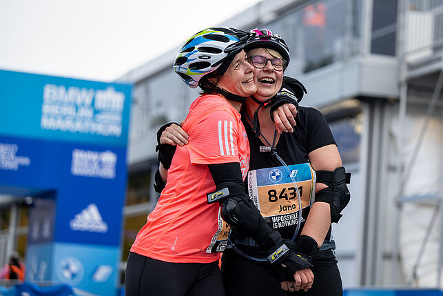 Two happy women hug each other exhausted at the finish line.