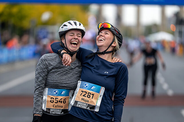 Two women embrace exuberantly at the finish line and show great joy.