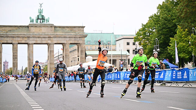 Various skaters have just passed through the Brandenburg Gate and are heading for the home straight, some of them cheering.